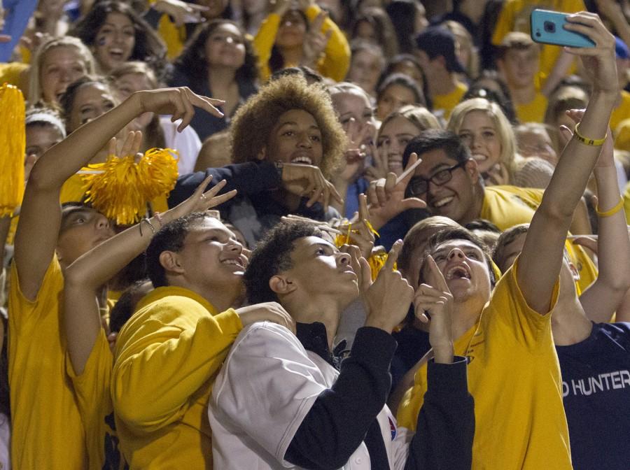 During the cross town showdown, senior Preston Smith takes a selfie with some of the crowd. The Lions fans had a gold out which meant everyone had to wear gold to support the team.