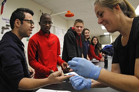 During a lab senior Fady Muwanes gets pricked by Ms.Harrison to draw blood. The lab helped students know what blood type they are.