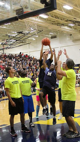 At the faculty-student basketball game, teachers and administrators surround junior Terrence Reid Sumter as he goes for the rebound.