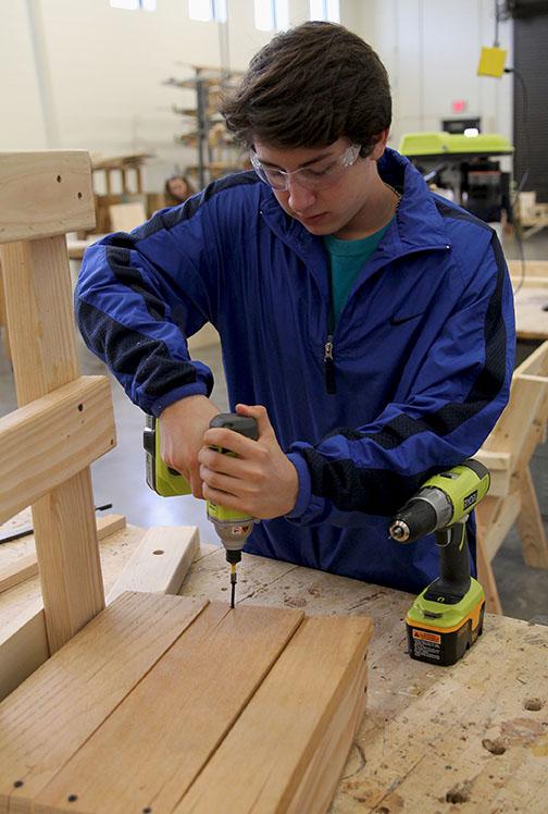 Freshman Ethan Kahnen drills a screw, while building a bench for construction management class. 