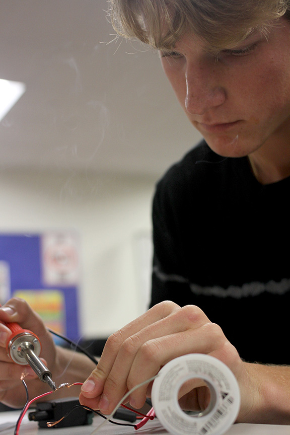 During Mr. McAfees robotic engineering class, sophomore Kyle Clark solders wires for a new project.

