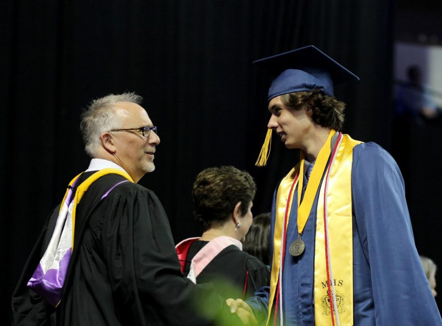 Graduate Jake Rogge shakes a teachers hand.