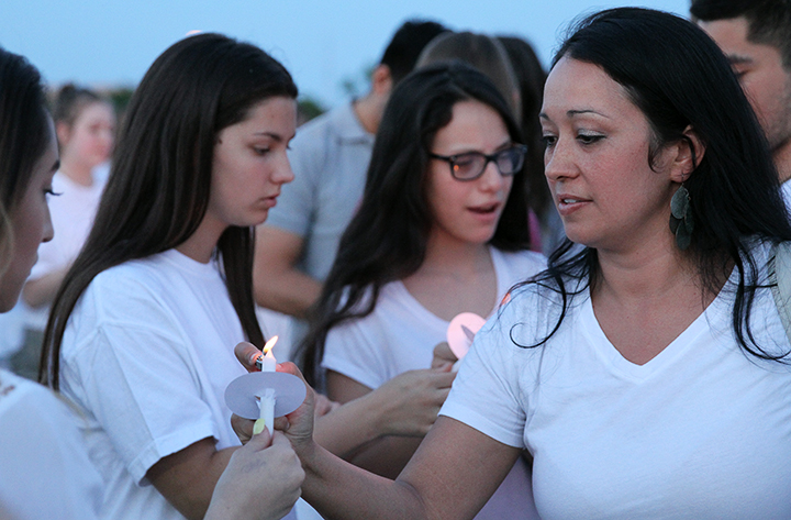 Community member helps light another persons candle.