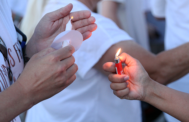 Two community members light a candle with a lighter.