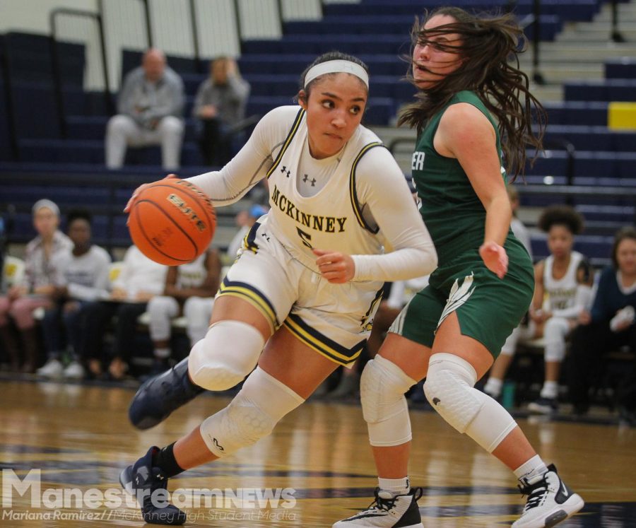While passing an opposing player, junior Trinity White dribbles the ball down the court.
